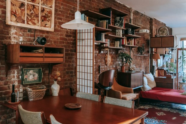 Dining zone and bed in stylish flat with brick walls