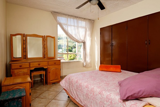 A bedroom with a bed, dresser, and mirror