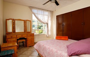 A bedroom with a bed, dresser, and mirror